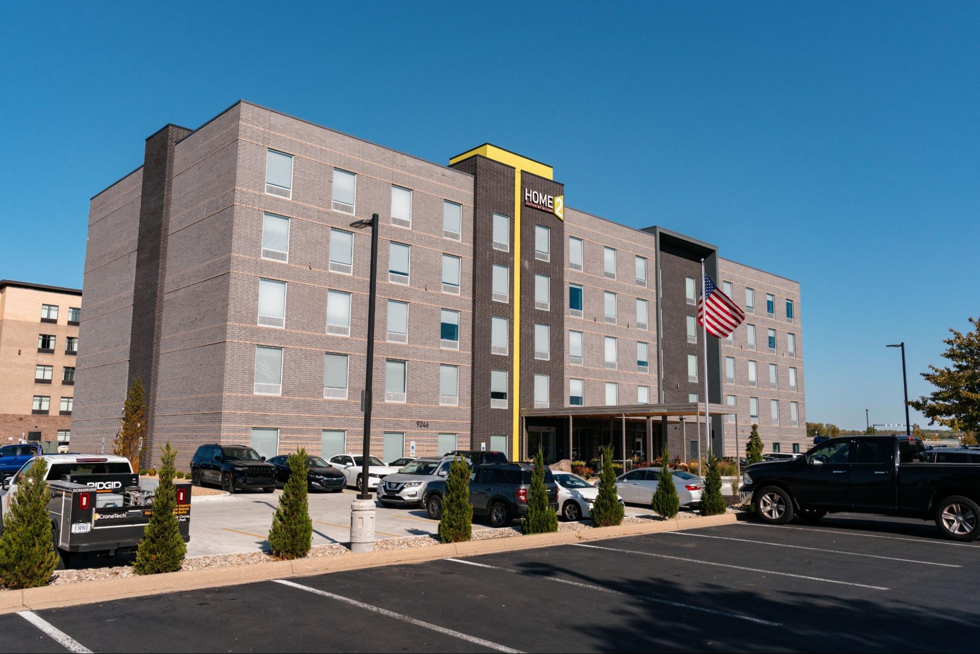 An ICF hotel features an awning at the entrance with a large parking lot surrounding the hotel.