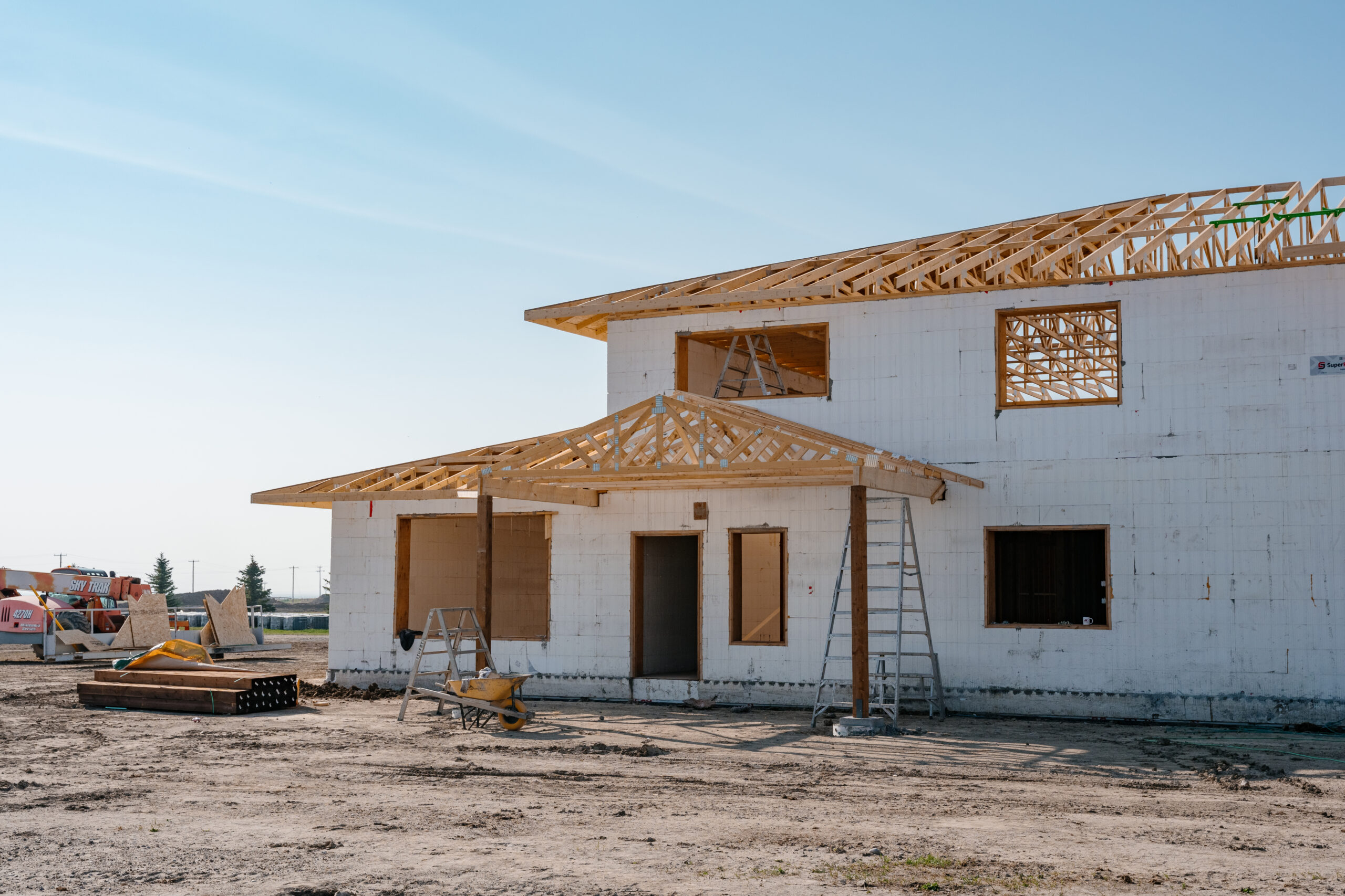 This image depicts a two-story home being built with ICF blocks and a wood-framed roof.