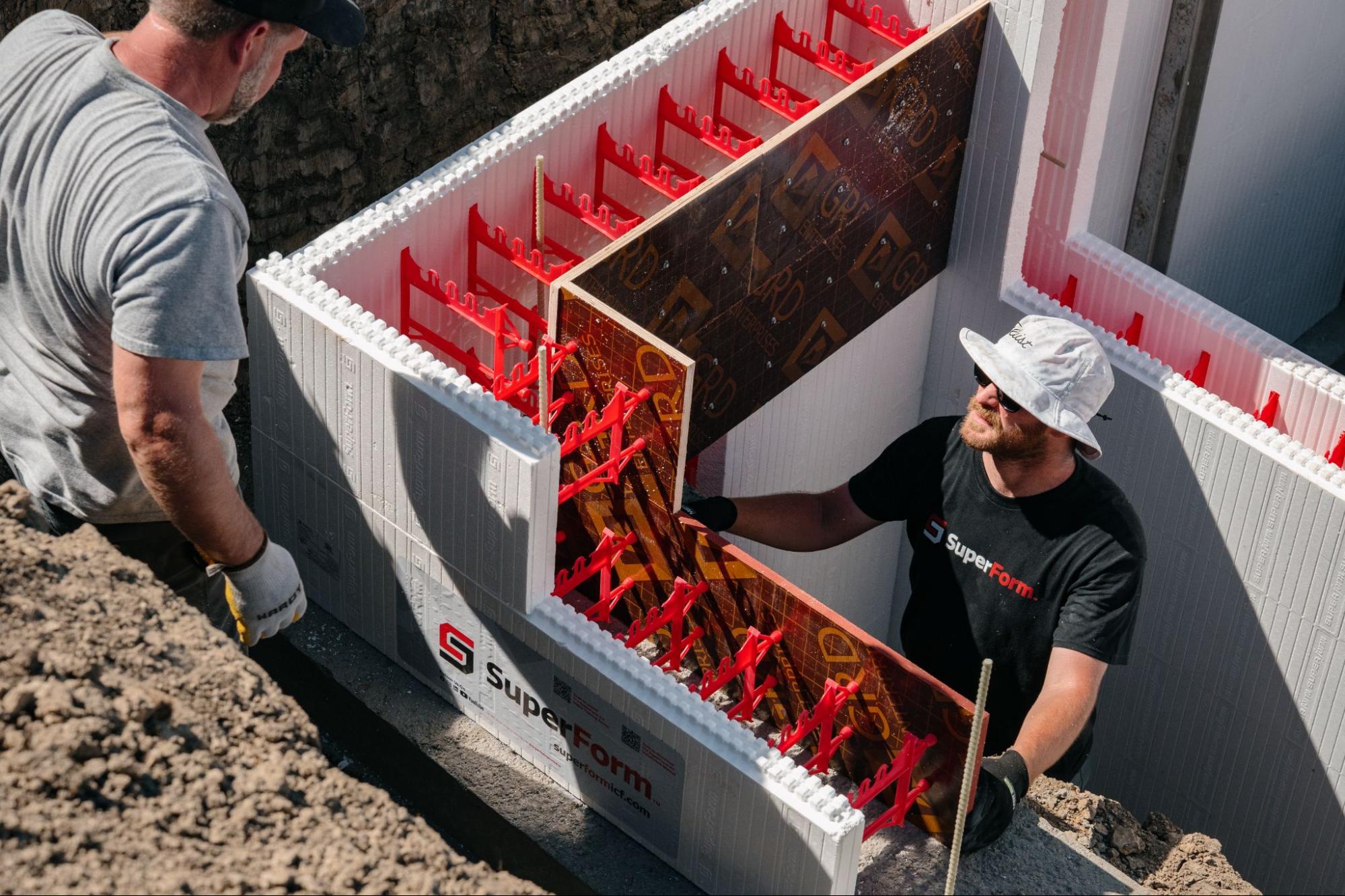 Two construction workers stack SuperForm one-sided ICF blocks at an active job site.