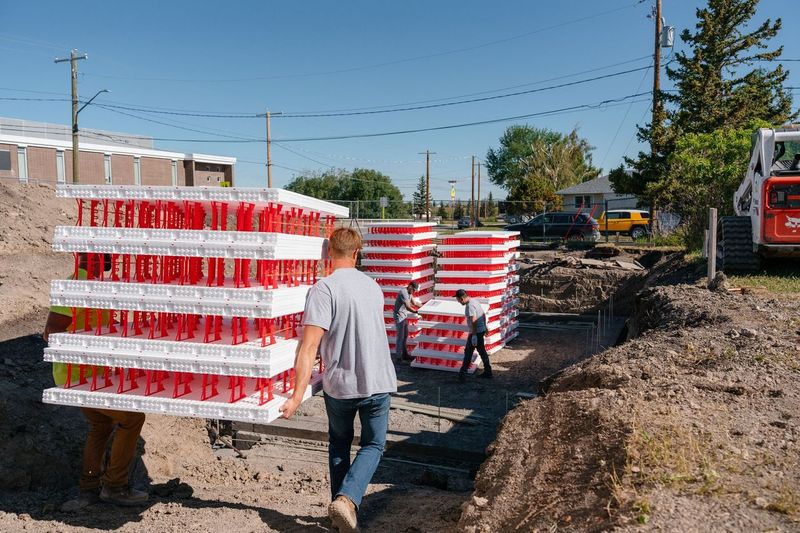 This image depicts two ICF experts carrying SuperForm’s ICF blocks on a job site.