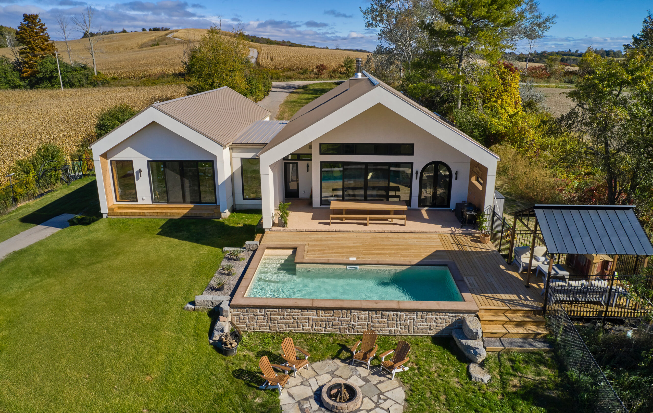 A modern house constructed with ICF (Insulated Concrete Form) blocks, featuring a spacious backyard that includes a swimming pool, a fire pit, and outdoor chairs arranged for seating.