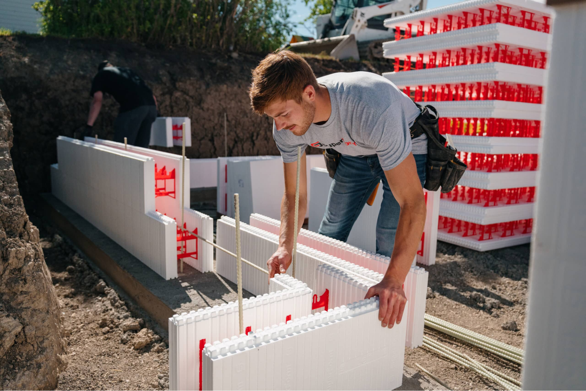 This image depicts a professional installing SuperForm ICF blocks on a construction site.