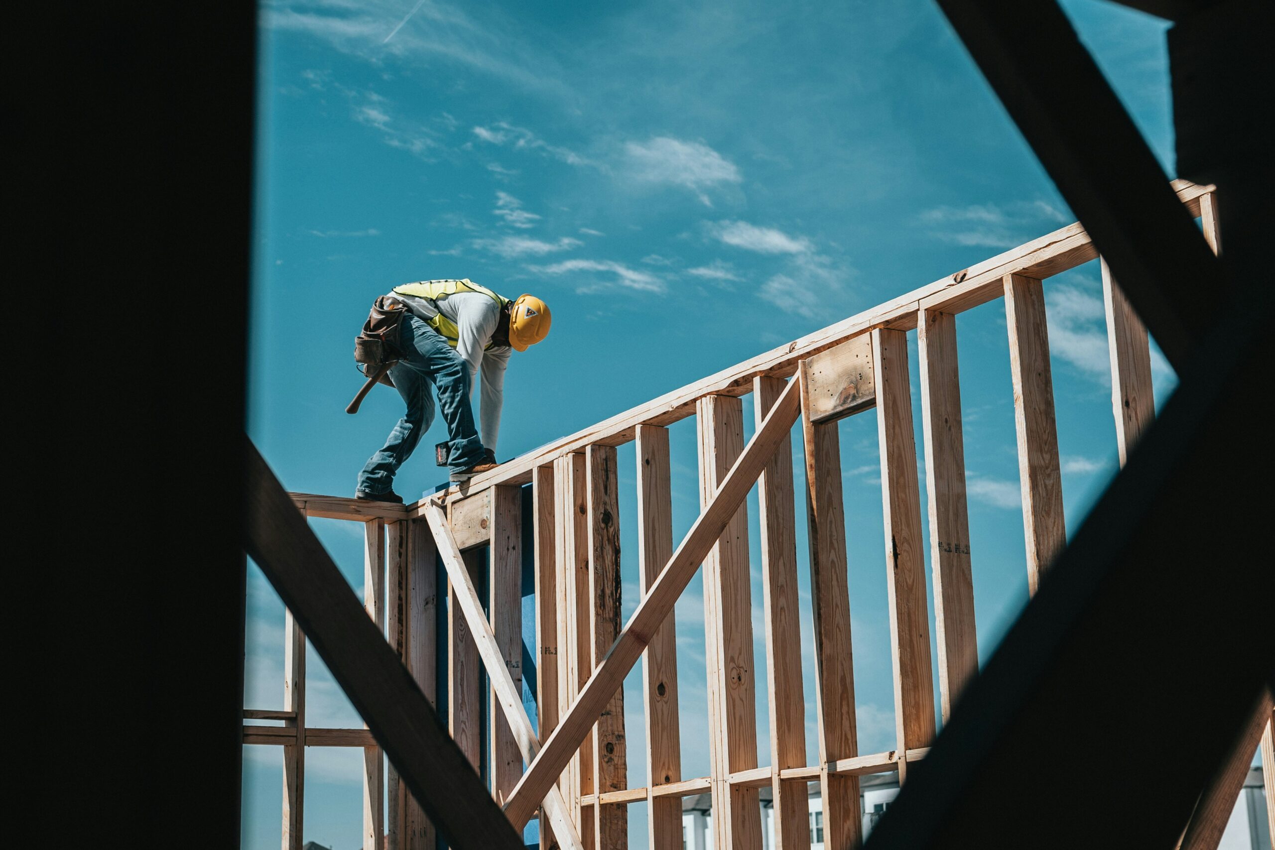 A professional wearing protective gear is building a wood-frame house.