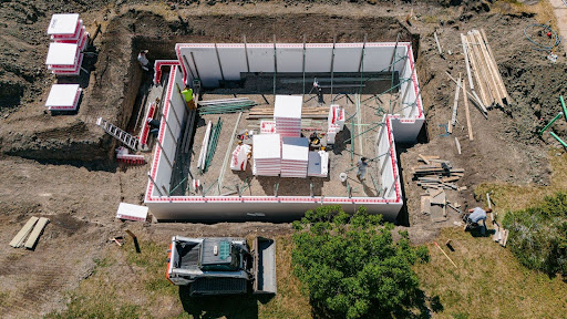 An aerial view shows professionals stacking SuperForm’s ICF blocks to form a home’s foundation.